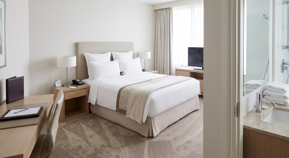 Hotelzimmer nach Reinigung: frisch bezogenes Bett, makellose Badarmaturen und gesaugter Teppich