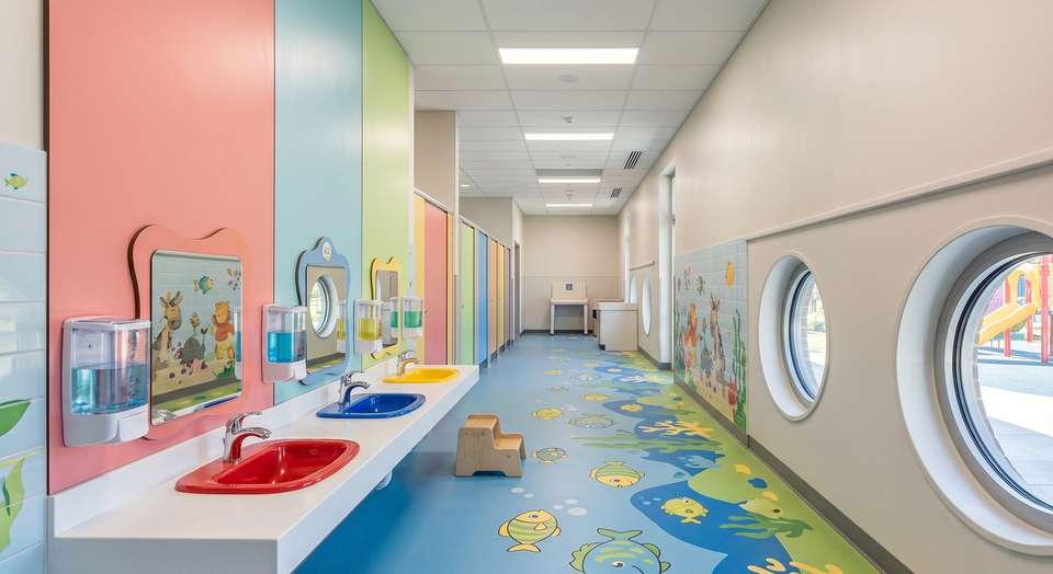 Kindgerechter Sanit&auml;rbereich: saubere Waschbecken in niedriger H&ouml;he, desinfizierte Griffe und gef&uuml;llte Spender